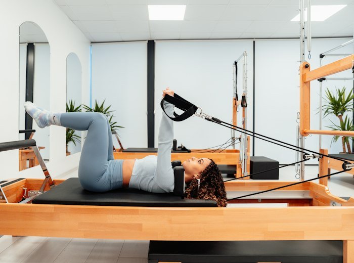 A member lying on a reformer with her feet in the straps